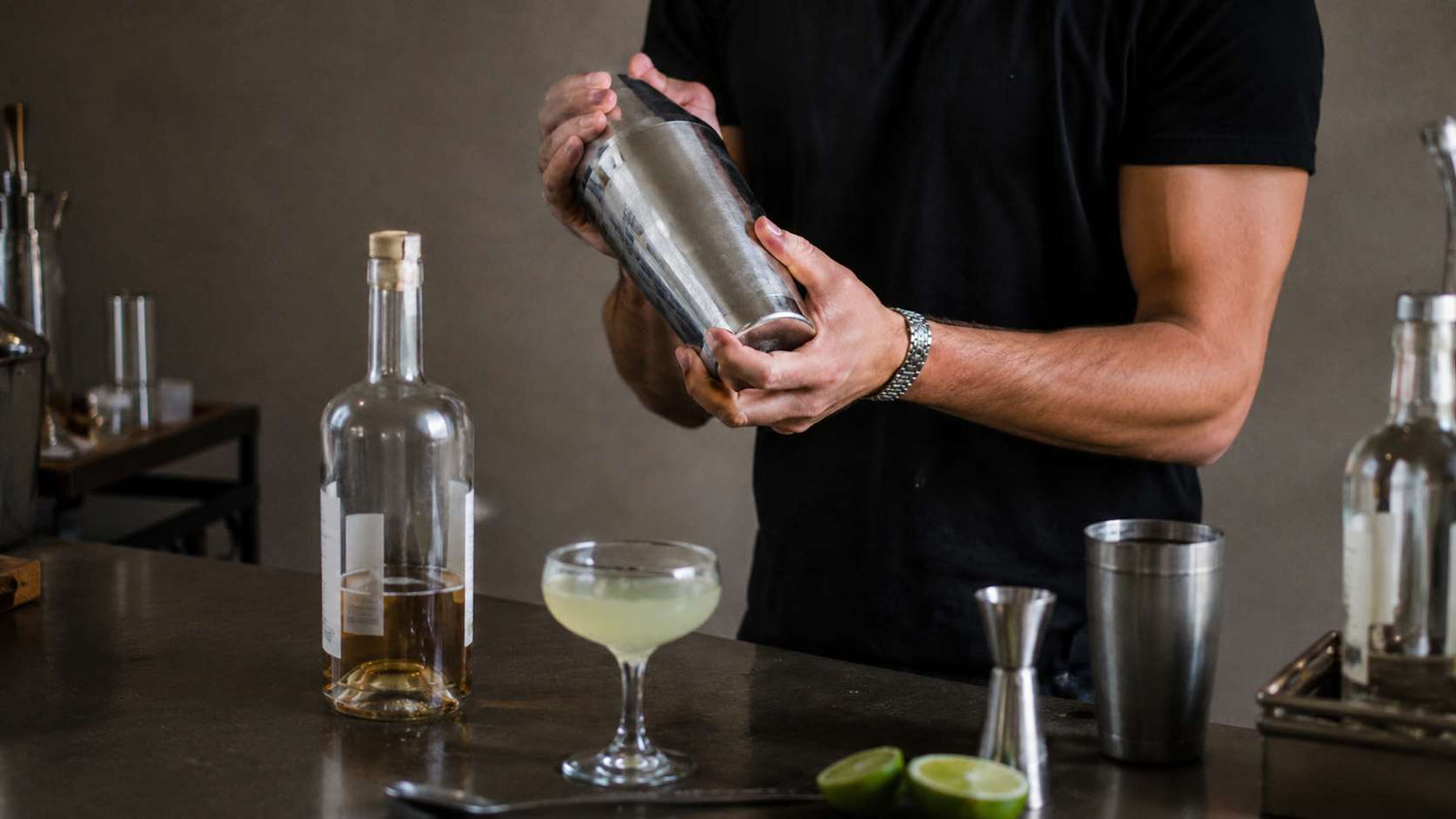 Bartender shaking a cocktail with a stainless steel shaker at a home bar