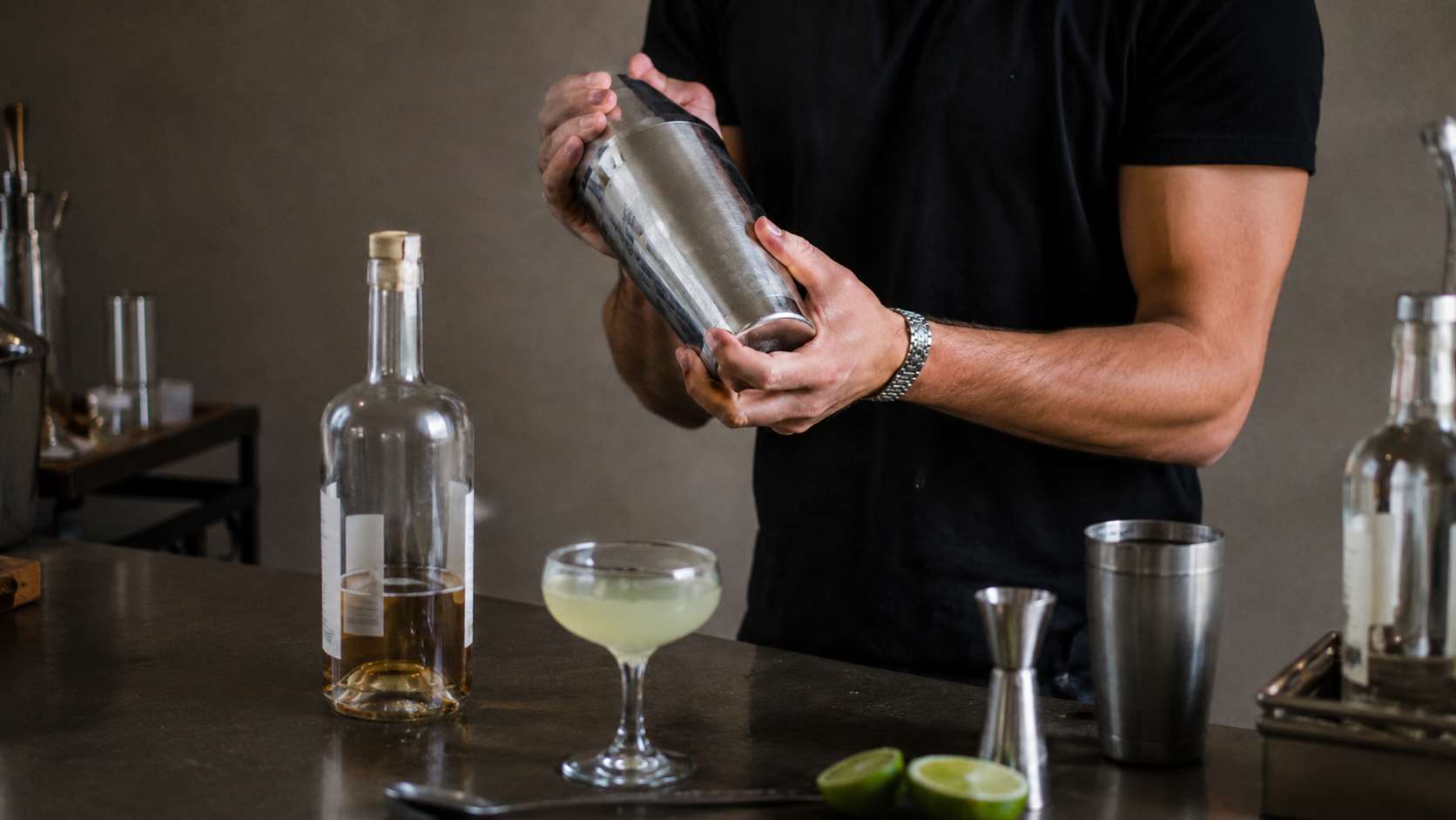 Bartender shaking a cocktail with a stainless steel shaker at a home bar