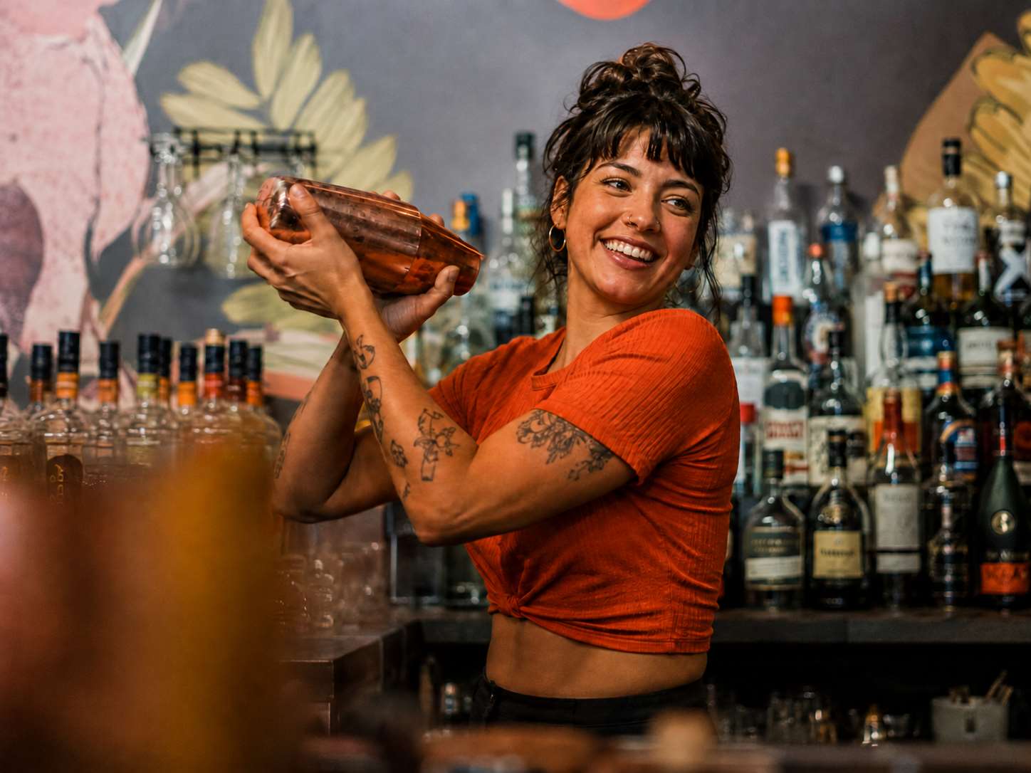 Professional bartender shaking a copper Boston cocktail shaker behind a commercial bar