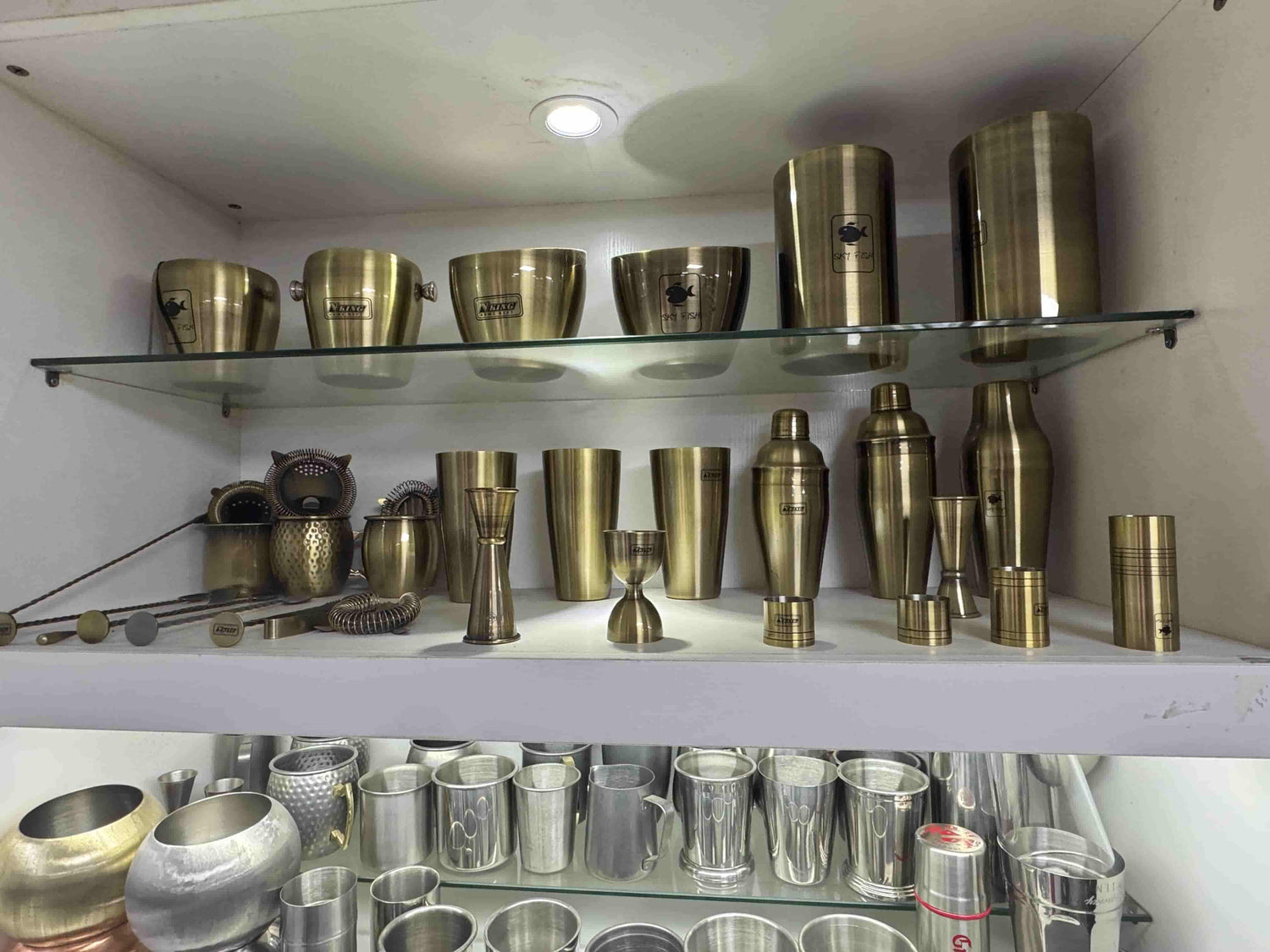 Brushed gold stainless steel barware display with shakers, jiggers, strainers, cups and ice buckets for wholesale sourcing