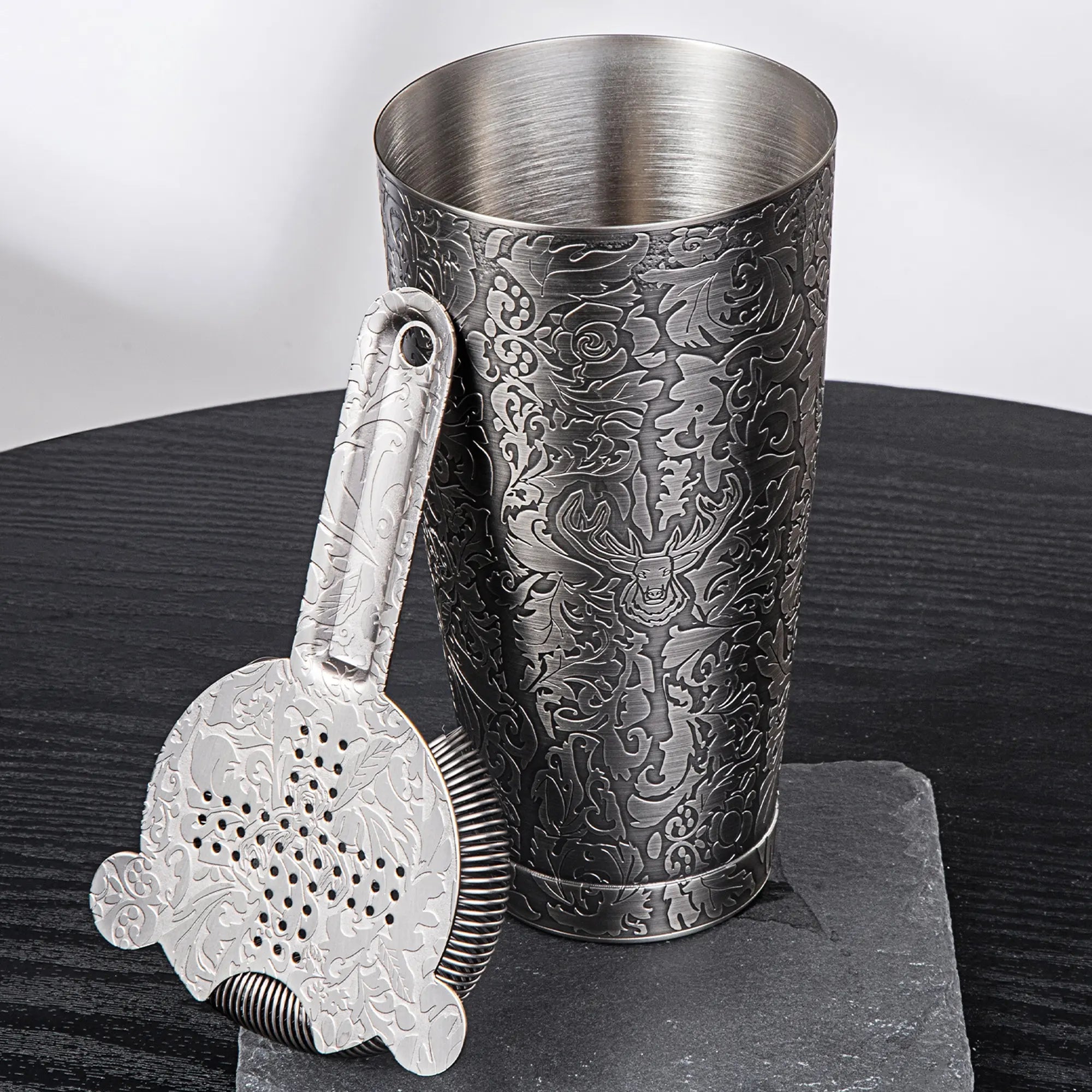 Metallic cocktail shaker with embossed design on a dark surface