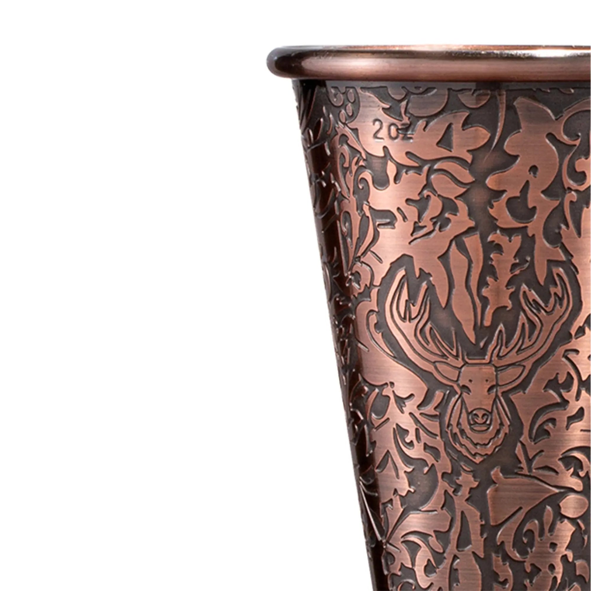 A macro close-up of an antique copper plated double jigger showing the 2oz measurement mark and detailed reverse-etched floral patterns.